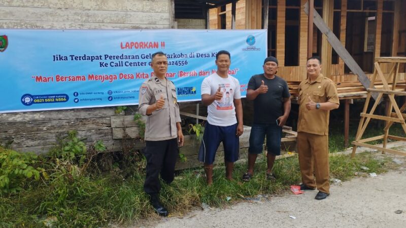 Bhabinkamtibmas Polsek Sabangau Dampingi Lurah Pasang Spanduk Anti-Narkoba di Bereng Bengkel